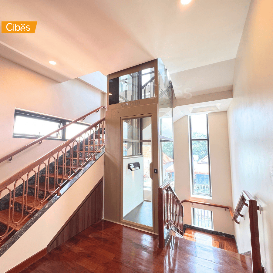 Cibes glass home lift, 1260 × 1360 mm, installed beside a wooden staircase in a residential home.