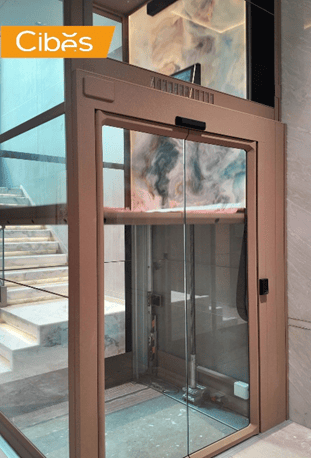 ជណ្តើរយន្តកញ្ចក់ Cibes សម្រាប់គេហដ្ឋាន ងាយស្រួលក្នុងការប្រើប្រាស់ដែលតម្លើងក្បែរជណ្ដើរជើងថ្មម៉ាប។