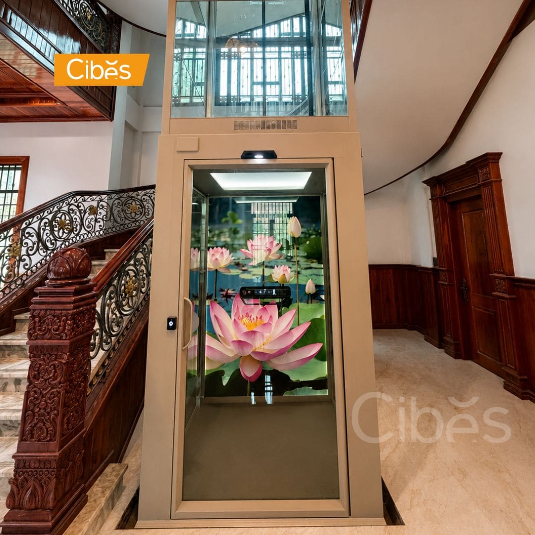 Pitless Cibes glass home elevator installed beside a staircase inside a luxury villa.